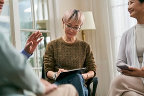 Asian female social worker or medical professional facilitating a group discussion for senior people.