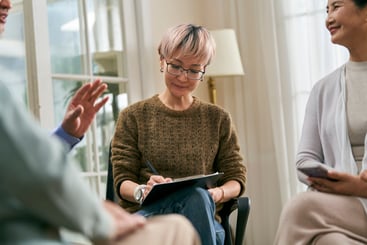Asian female social worker or medical professional facilitating a group discussion for senior people.