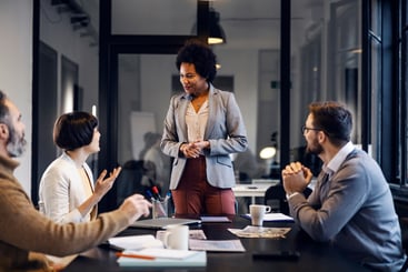 A multiracial female team leader is having business meeting with employees in the office.