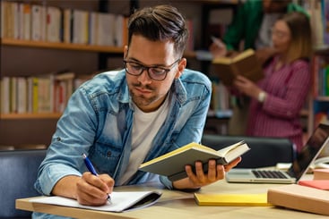 Young male student study in the library reading book.
